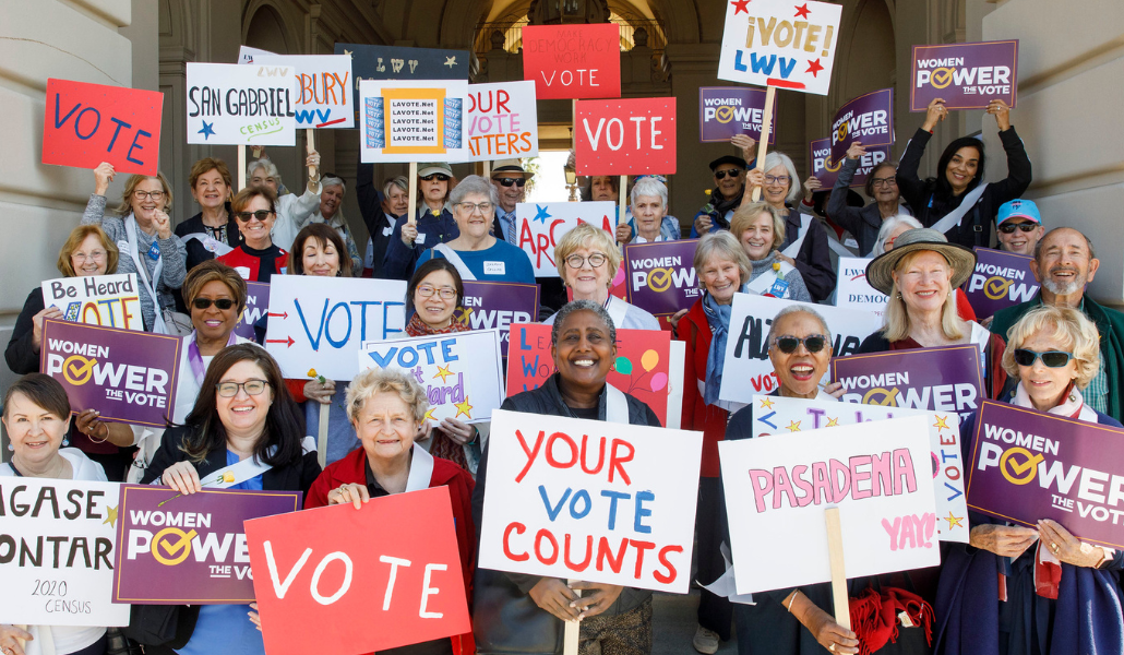 Group of women holding signs that read "Vote" and "Your Vote Counts"