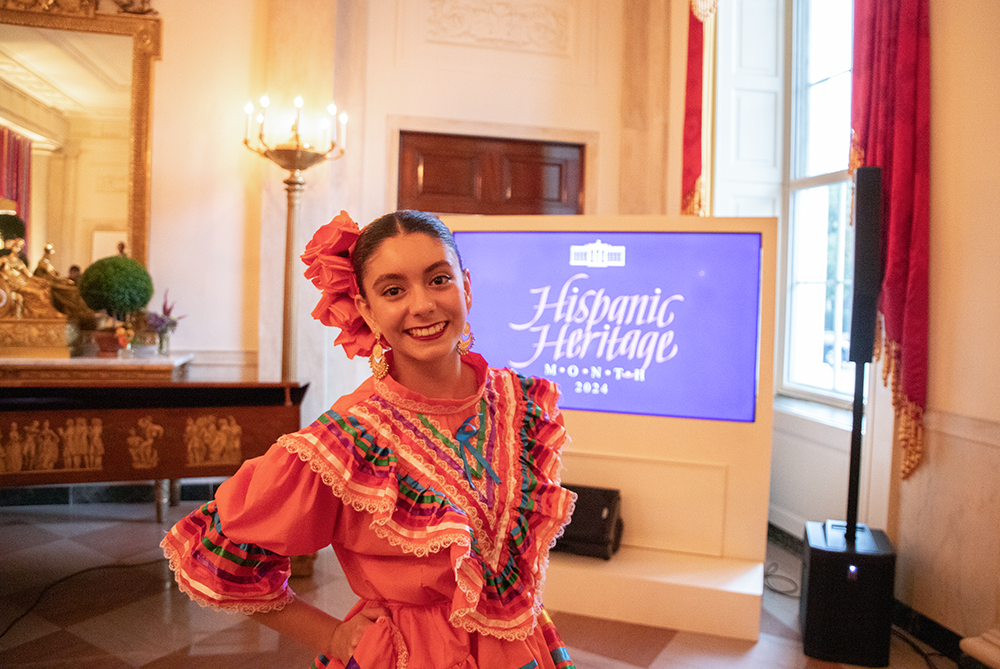 Student in front of a screen that reads Hispanic Heritage