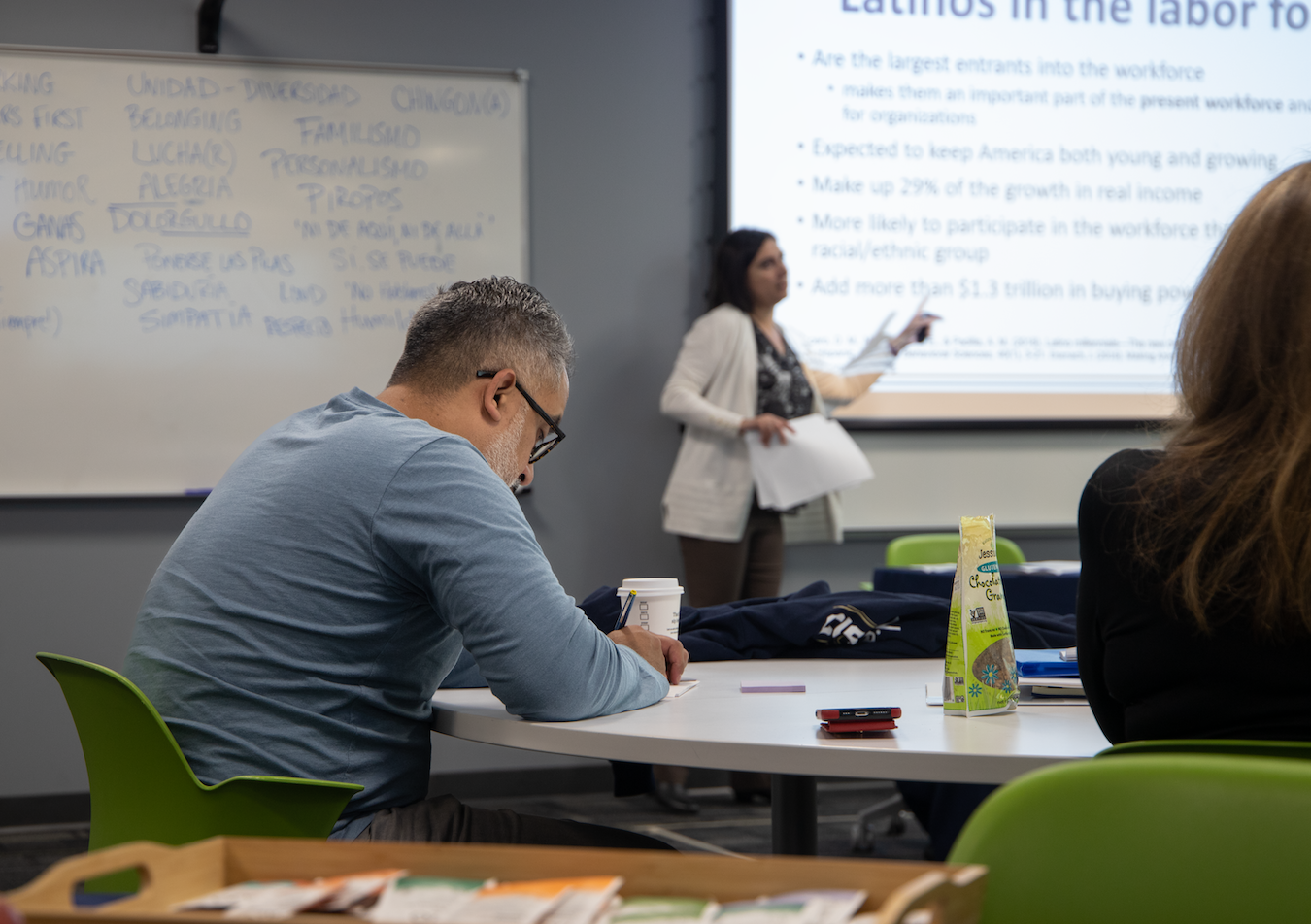 man writes while woman gives lecture