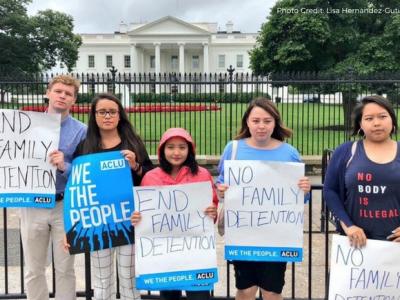 Five people holding up signs that read "End family detention" and "We the people"