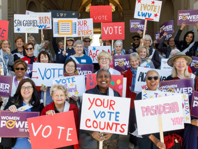 Group of women holding signs that read "Vote" and "Your Vote Counts"