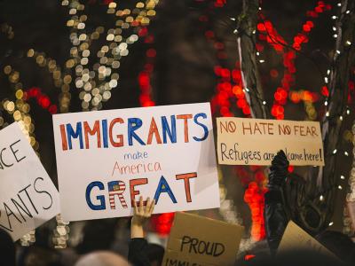 Hands in a protest holding up signs, including "Immigrants Make America Great"