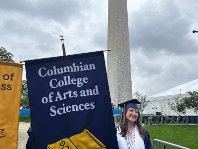 Student holding up a flag that reads, "Columbian College of Arts and Sciences"