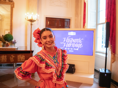 Student in front of a screen that reads Hispanic Heritage
