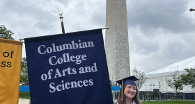 Student holding up a flag that reads, "Columbian College of Arts and Sciences"
