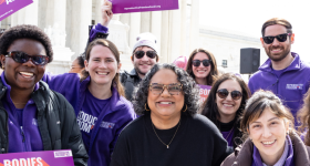 People standing in front of Supreme Court with sign that reads, "Reproductive Freedom for All"