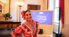 Student in front of a screen that reads Hispanic Heritage